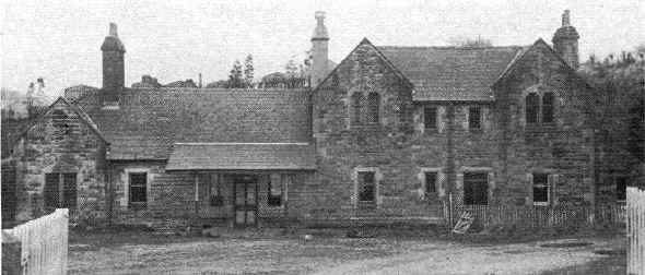 Roadside view of Arkholme Station to show the full front elevation. The stationmaster's garden is fenced off from the yard