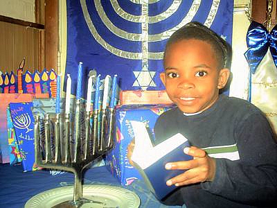 Takruri Jewish boy with de Sola Pool siddur at Chanukah menorah