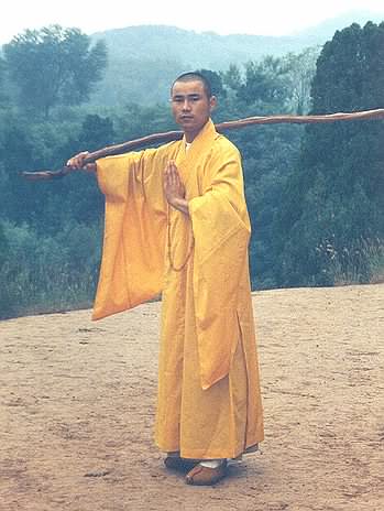 Picture of Master Xing Du with wooden staff on his shoulder.