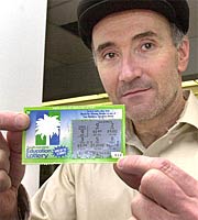 Dennis Browning, holds up his winning ticket after playing South Carolina's Education Lottery scratch and win game today, at a fitness center in Greenville. Browning won one dollar. And then and millions others were burned to a crips by the Hand of God. (AP)